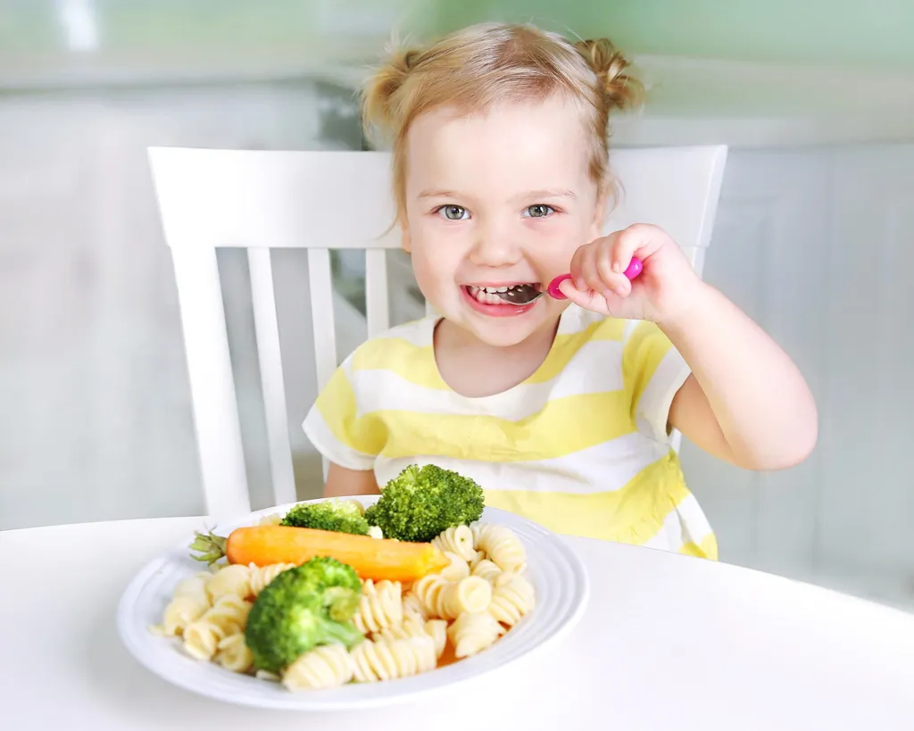 Une petite fille heureuse mangeant des légumes