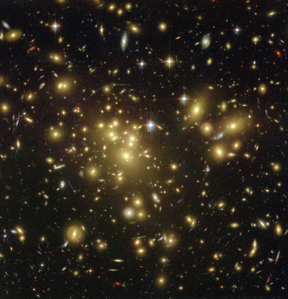 Un amas massif de galaxies jaunâtres, apparemment pris dans une toile d'araignée rouge et bleue de galaxies d'arrière-plan sinistrement déformées, constitue une image envoûtante de Hubble. Pour réaliser cette image sans précédent du cosmos, Hubble a scruté directement le centre de l'un des amas de galaxies les plus massifs connus, appelé Abell 1689. La gravité des milliards d'étoiles de l'amas - plus la matière noire - agit dans l'espace comme une 