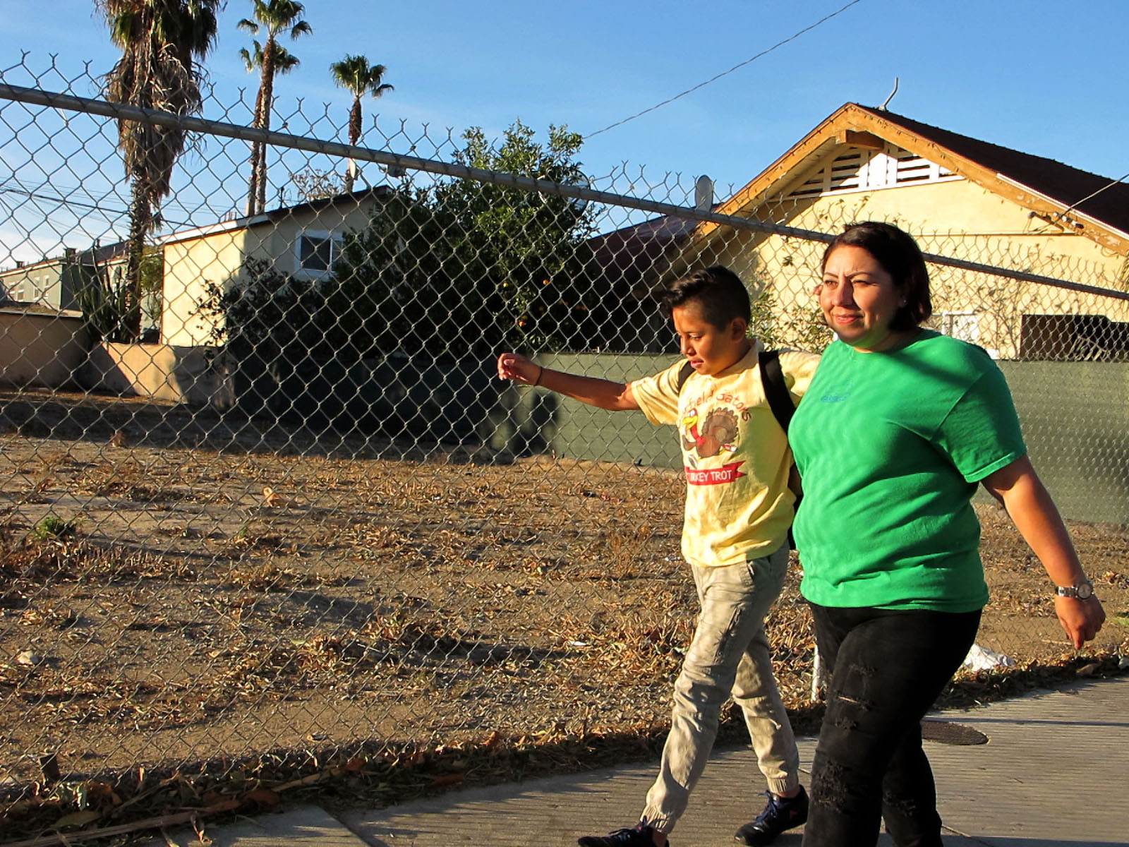 Photo d'un parent de Santa Ana accompagnant son fils à l'école près d'un terrain en terre vacant