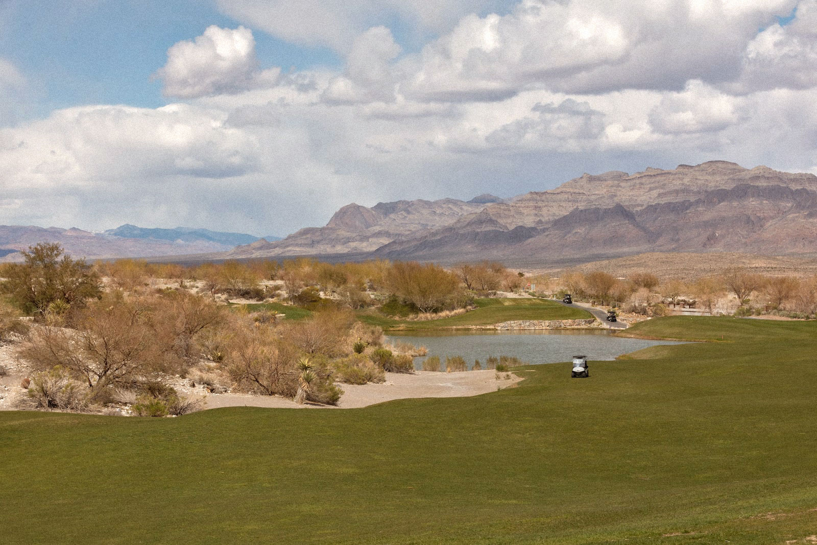 un terrain de golf vert à côté de montagnes sèches