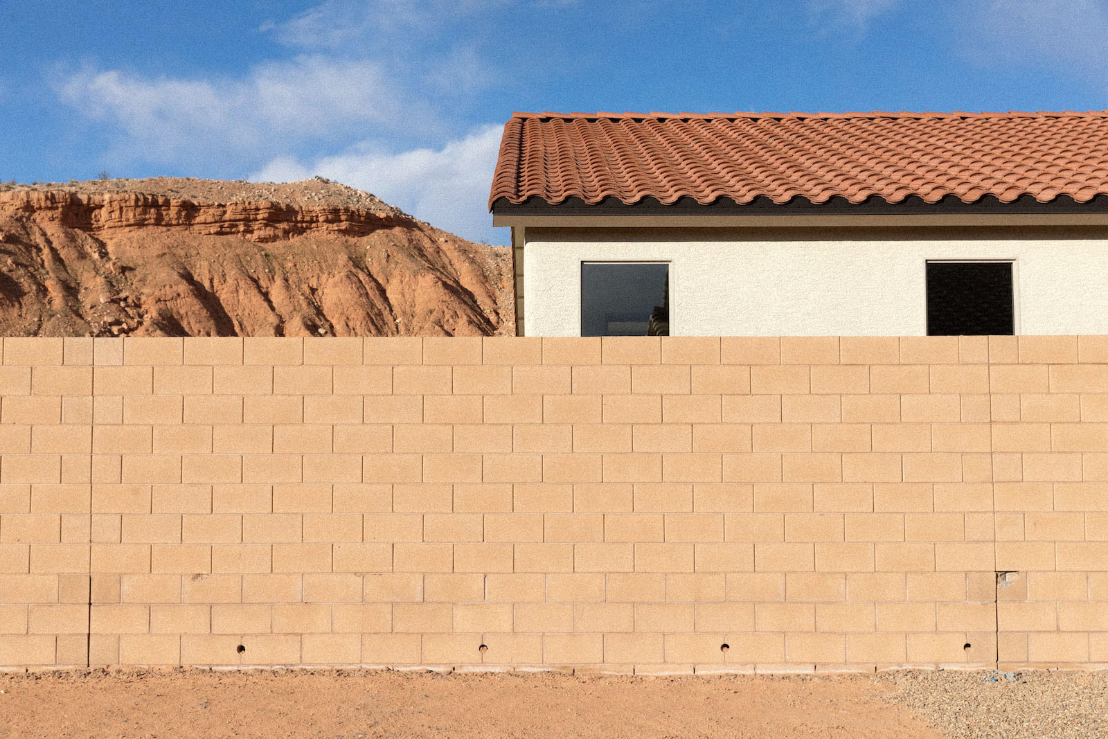 un mur de briques de sable près d'une maison et de montagnes