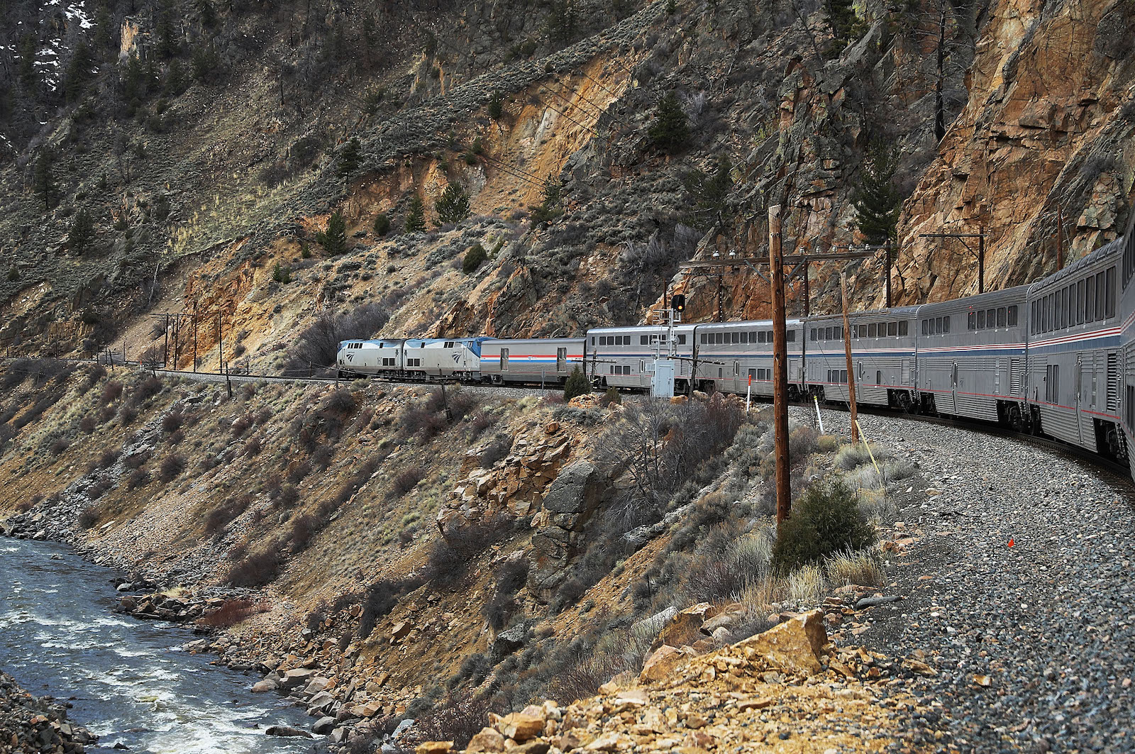 un train de voyageurs longe une falaise rocheuse