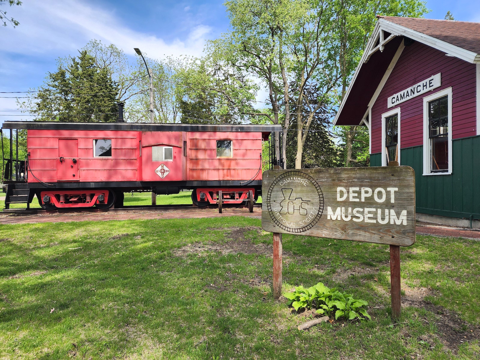 Un wagon de train rouge se trouve à l'extérieur du musée du dépôt de la Société historique de Camanche.
