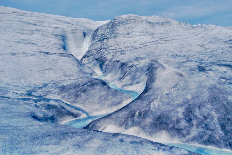 L'eau de fonte se déverse sur la calotte glaciaire du Groenland dans un canal sinueux.