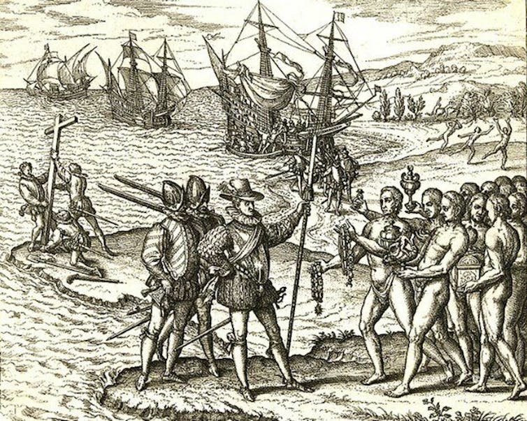 Une gravure en noir et blanc d'un groupe d'hommes armés et blindés debout sur le rivage parlant à de nombreux hommes nus. De grands navires naviguent en arrière-plan.
